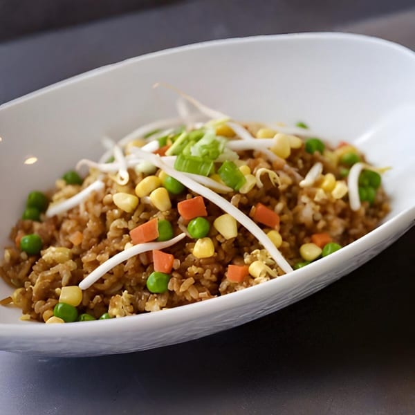 A white bowl filled with Lotus Xpress fried rice, topped with bean sprouts, corn, peas, and carrots.