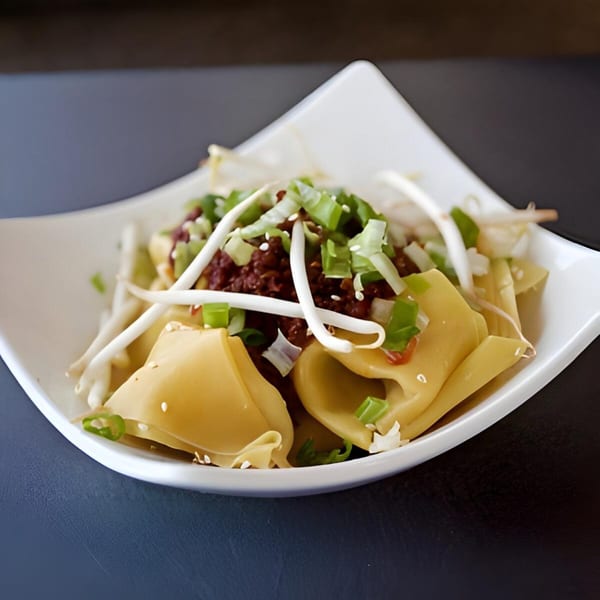Lotus Xpress's Chinese noodles with ground meat, bean sprouts, and green onions in a white bowl.